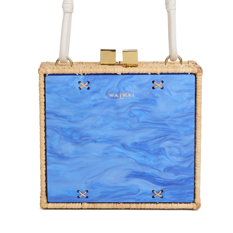 Bolsa estruturada quadrada em rattan, frente em acrílico marmorizado azul, estampa de peixes espelhados e alça longa em couro branco.
