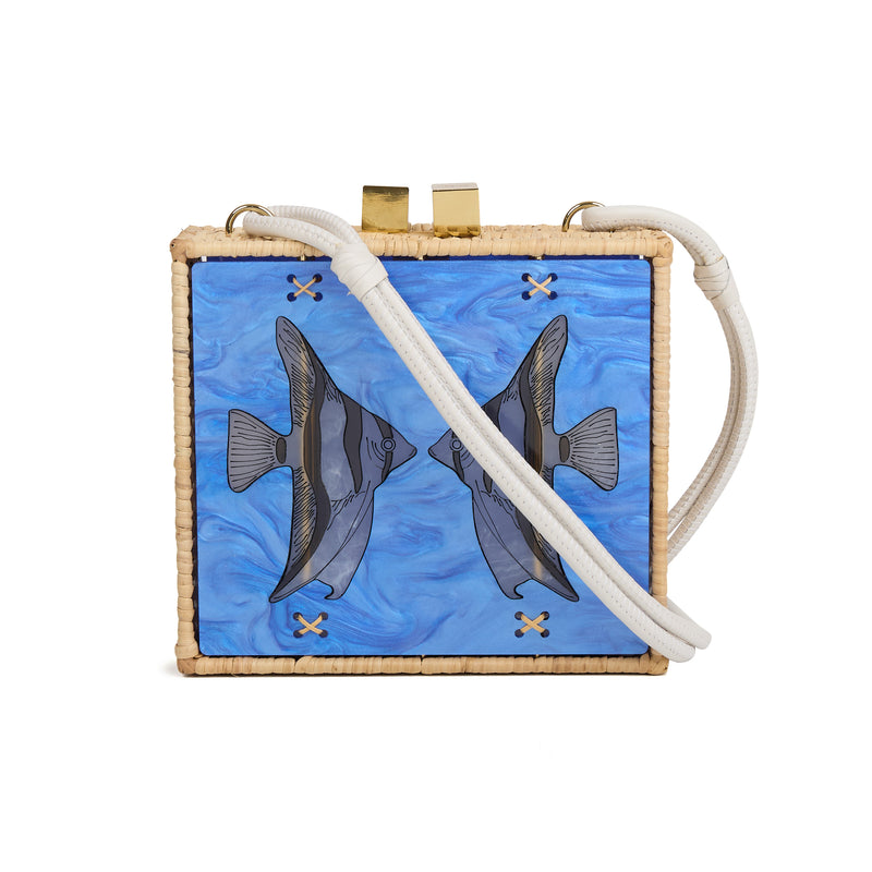 Bolsa quadrada estruturada em rattan com painel em acrílico marmorizado azul, estampa de dois peixes espelhados ao centro, fecho metálico dourado e alça longa em couro branco.