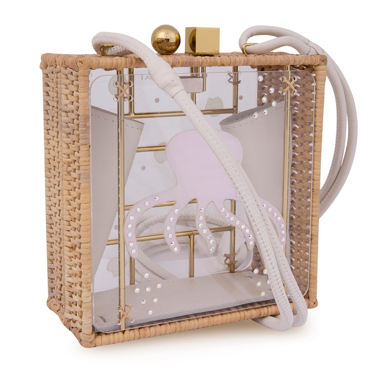 Bolsa quadrada com estrutura em rattan e acrílico transparente, estampa de polvo rosa ao centro com detalhes brilhantes, fecho metálico dourado e alça longa em couro claro.