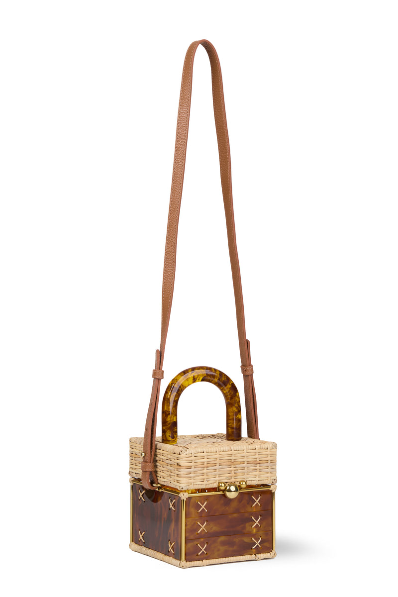 Bolsa pequena estruturada em rattan natural com base em acrílico marrom marmorizado, detalhe de costura em X e alça rígida em acrílico marmorizado marrom.