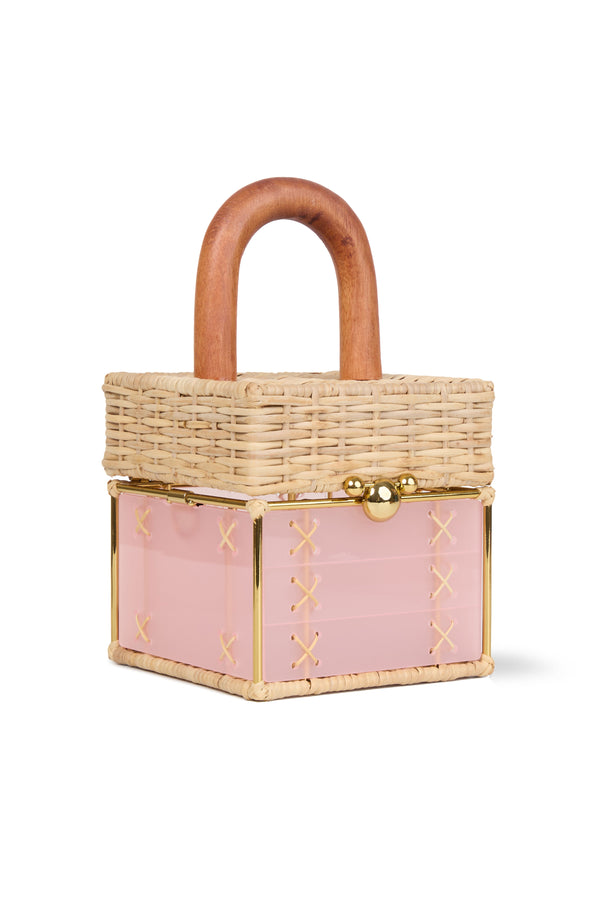 Bolsa pequena estruturada em rattan natural com base em acrílico rosa translúcido, detalhe de costura em X e alça rígida em madeira.
