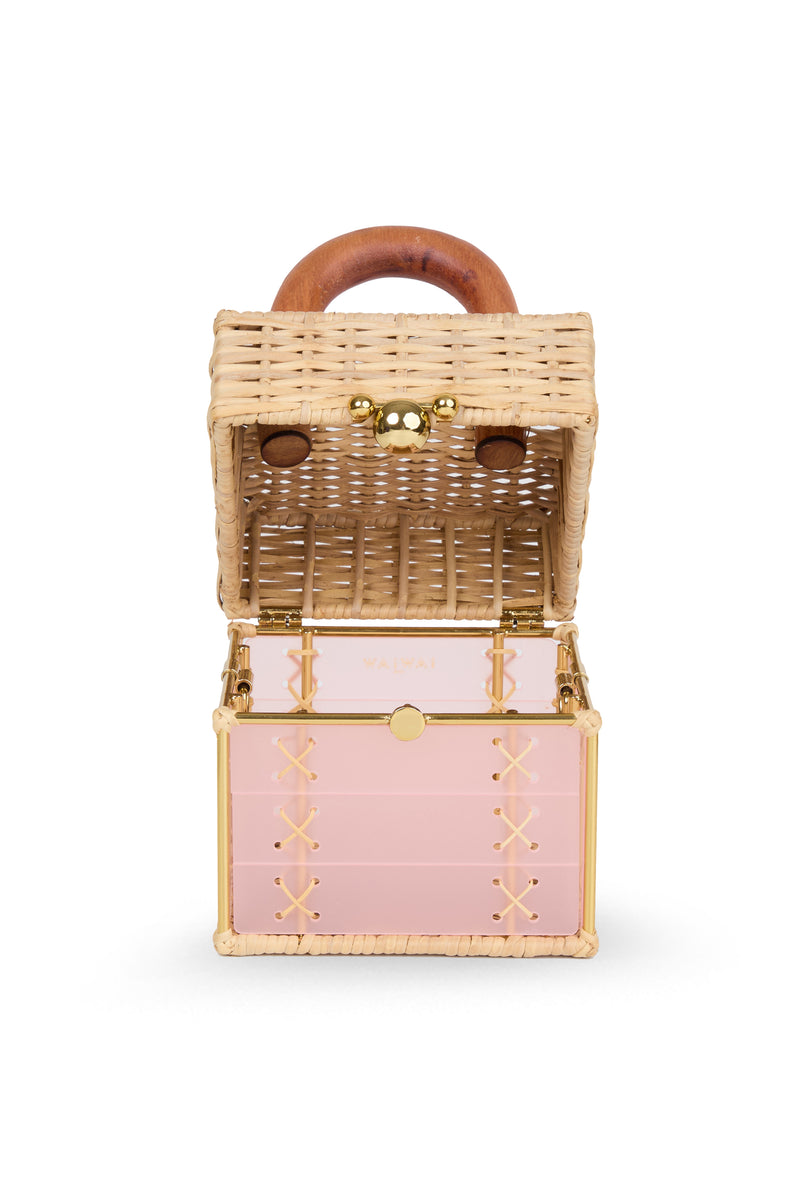 Bolsa pequena estruturada em rattan natural com base em acrílico rosa translúcido, detalhe de costura em X e alça rígida em madeira.