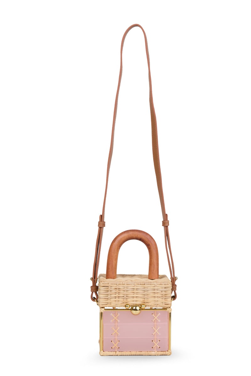 Bolsa pequena estruturada em rattan natural com base em acrílico rosa translúcido, detalhe de costura em X e alça rígida em madeira.