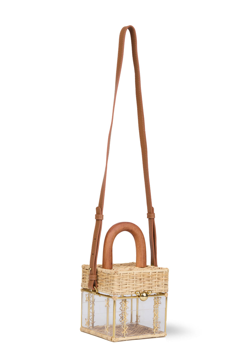 Bolsa pequena estruturada em rattan natural com base em acrílico transparente, detalhe de costura em X e alça rígida em madeira.