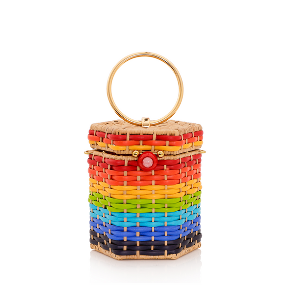 Bolsa estruturada em rattan com trama em degradê de cores do arco-íris, fecho esférico vermelho e alça metálica circular dourada.