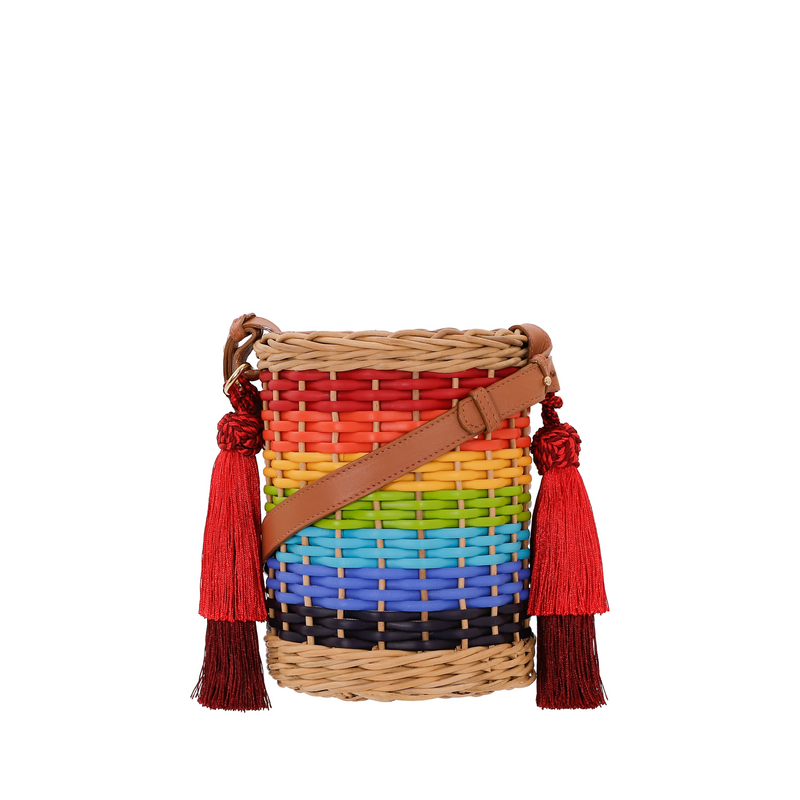 Bolsa estruturada em rattan com trama em degradê de cores do arco-íris, alça longa em couro marrom e tassels vermelhos laterais.