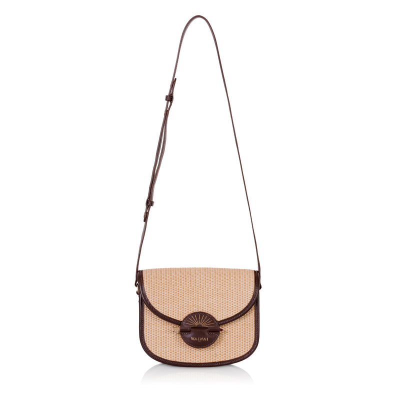 Bolsa Waiwai em rattan natural com acabamento em couro marrom e fecho redondo central em resina marrom com detalhe dourado.