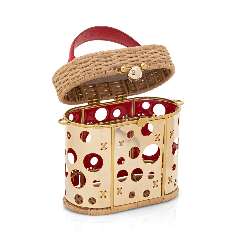 Bolsa estruturada em rattan com painel frontal dourado vazado em círculos, alça curta em couro vermelho e fecho dourado.