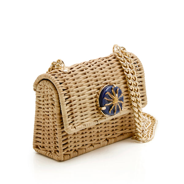 Bolsa artesanal em rattan com aplique redondo azul marinho e sol dourado no centro, alça de corrente metálica dourada.