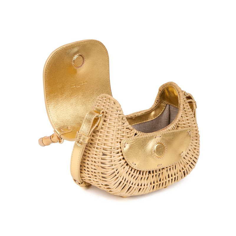 Bolsa em rattan natural com estrutura rígida, flap de couro dourado, detalhe azul arredondado e alça em bambu.