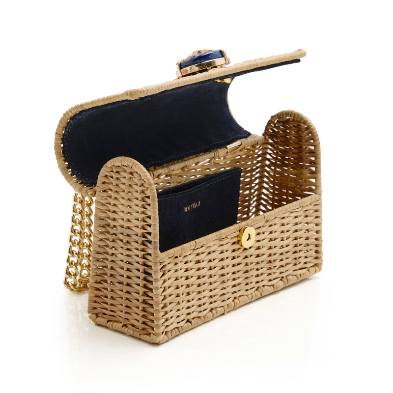 Bolsa artesanal em rattan natural grande, com ornamento central azul marinho e sol dourado, alça longa metálica dourada.