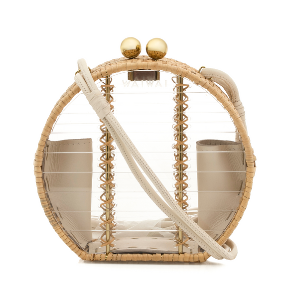 Bolsa estruturada redonda em acrílico transparente com detalhes em rattan natural nas bordas. Possui alça longa em couro bege removível, fecho de esferas douradas e interior com compartimentos laterais em couro bege.