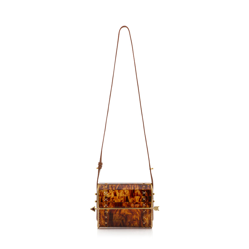 Bolsa em acrílico tartaruga estruturada com laterais em palha natural, fecho dourado em formato de flecha e amarrações artesanais nas laterais.