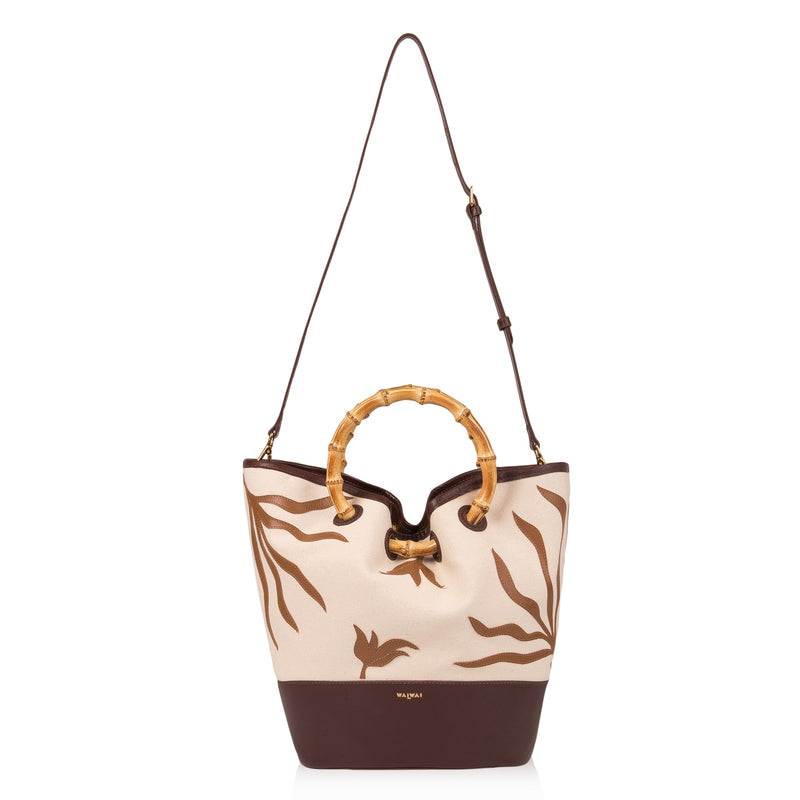 Bolsa tote em tecido cru bordada em marrom, base sólida marrom e alça de bambu estruturada.