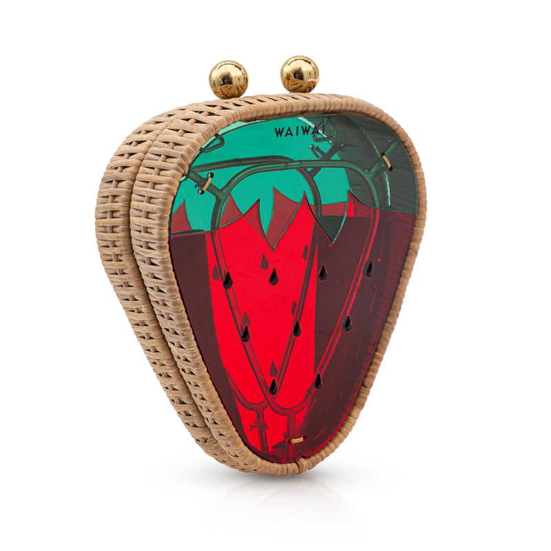 Bolsa artesanal triangular em rattan, com detalhe em acrílico colorido que lembra um morango, nas cores verde, vermelho e preto, e fecho dourado.