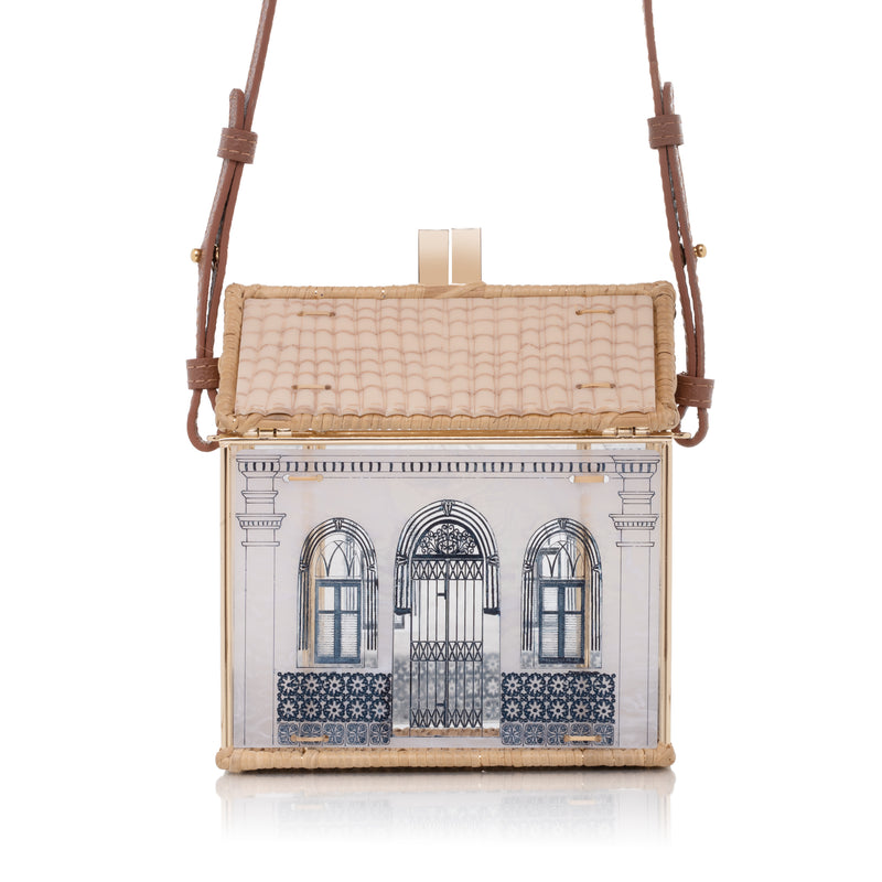 Bolsa estruturada em formato de casa, feita em acrílico branco e vime trançado, com janelas e portas azuis inspiradas no bairro do Carmo.