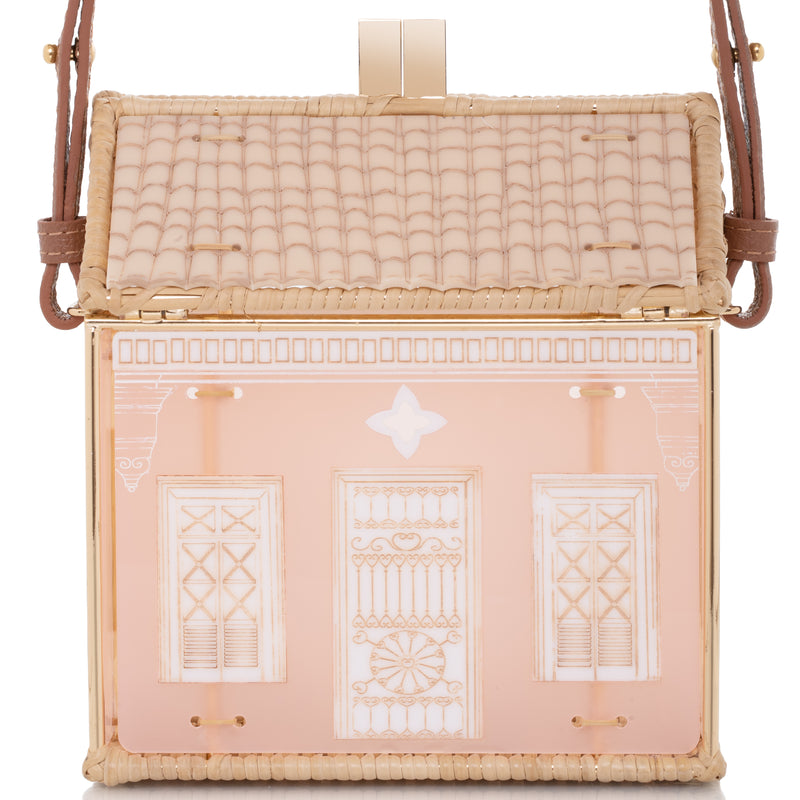 Bolsa autoral em acrílico nude e vime natural, inspirada nas casas coloniais do Humaitá, com detalhes arquitetônicos e estrutura dourada.