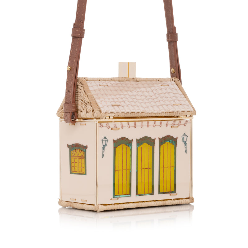 Bolsa estruturada em formato de casa, feita em acrílico nude e vime trançado, com portas coloridas inspiradas em Paraty.