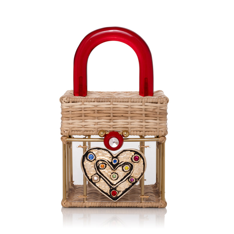 Bolsa estruturada em vime e acrílico transparente, com coração dourado cravejado de cristais coloridos e alça vermelha em acrílico.