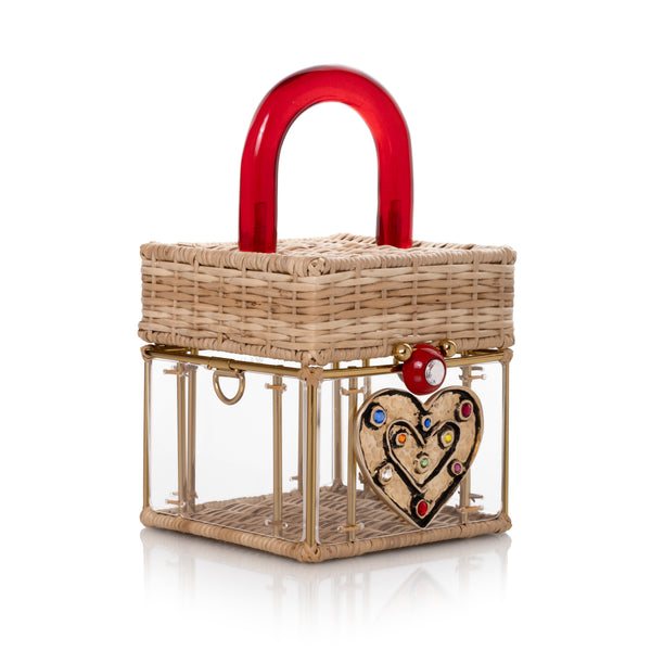 Bolsa artesanal em vime natural, corpo em acrílico transparente, detalhe de coração dourado com cristais e alça vermelha.