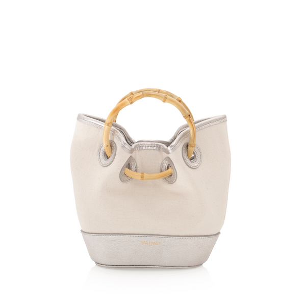 Bolsa bucket em canvas cru com detalhes em couro prata. Possui alça de mão em bambu curvado e acabamento em couro na base e nas bordas superiores.