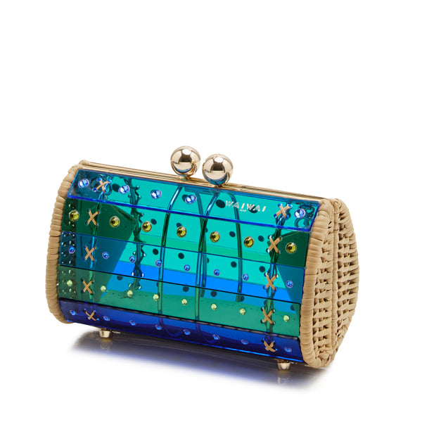 Clutch estruturada em acrílico azul e verde translúcido, aplicações geométricas, detalhes em palha nas laterais e fecho dourado esférico.