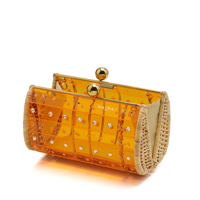 Clutch em acrílico laranja translúcido com ornamentos geométricos, laterais em palha e fecho metálico dourado redondo.