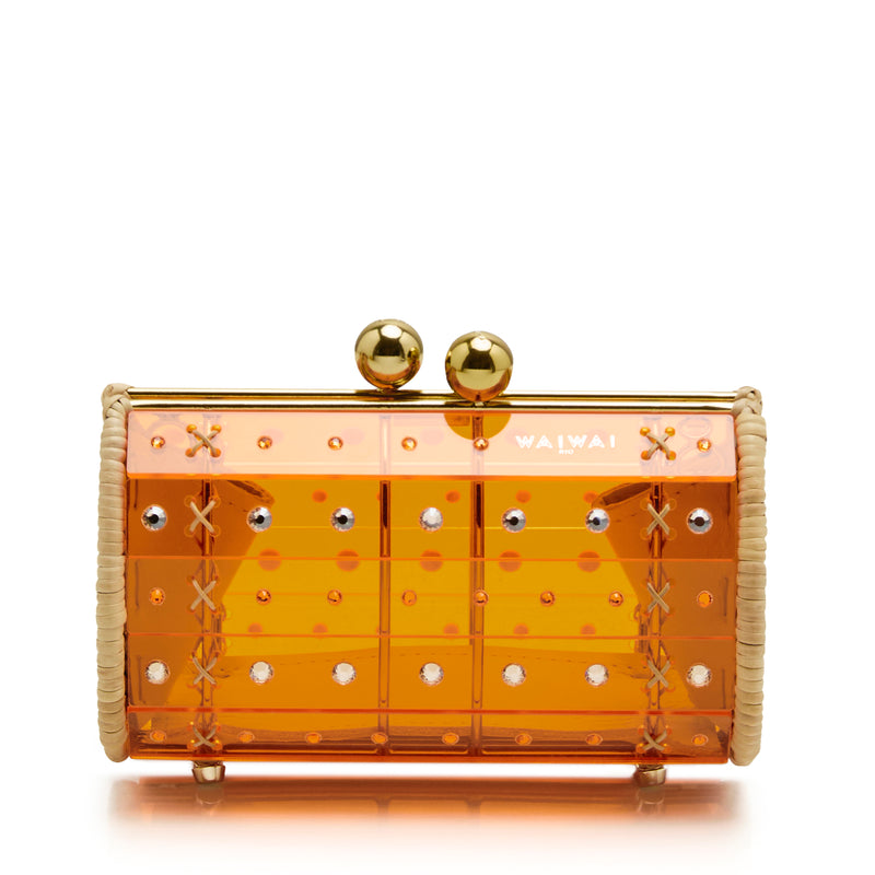Clutch em acrílico laranja translúcido com aplicações geométricas, detalhes em palha nas laterais e fecho esférico dourado.