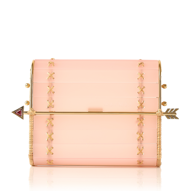 Clutch em acrílico rosa translúcido com laterais em rattan, detalhe de costura em X dourado e fecho em formato de flecha metálica dourada com ponta vermelha.