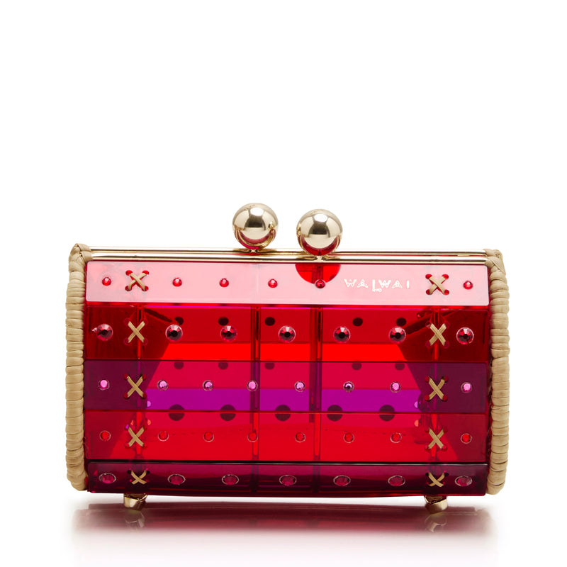 Clutch em acrílico vermelho translúcido com aplicações geométricas, detalhes em palha nas laterais e fecho esférico dourado.