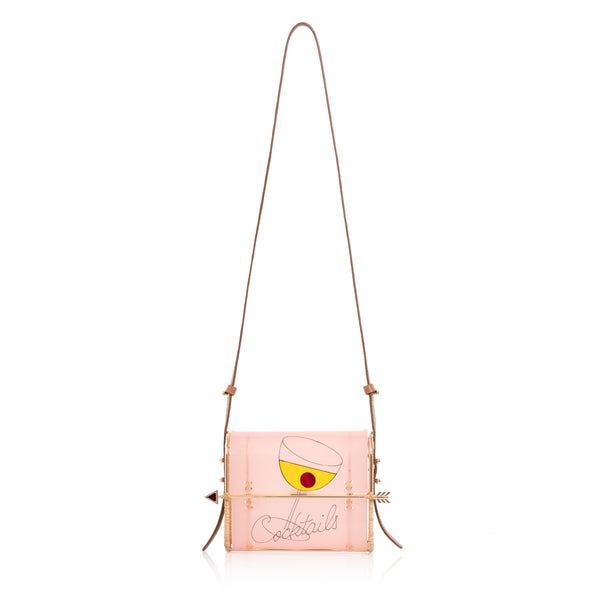 Clutch em acrílico rosa translúcido com estampa de taça de coquetel amarela, inscrição “Cocktails” e fecho de flecha dourada.
