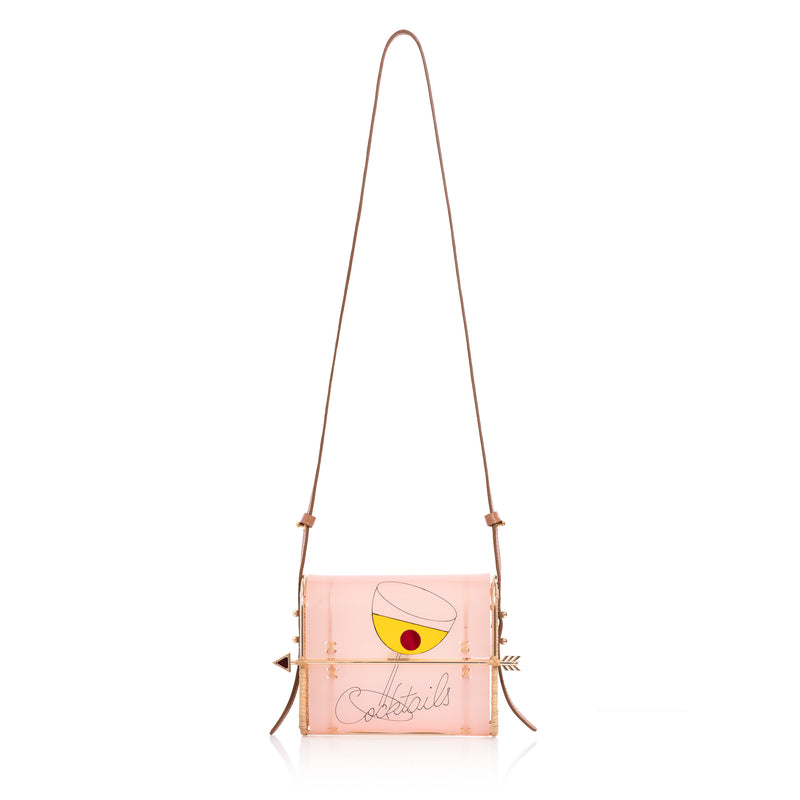 Clutch em acrílico rosa translúcido com estampa de taça de coquetel amarela, inscrição “Cocktails” e fecho de flecha dourada.