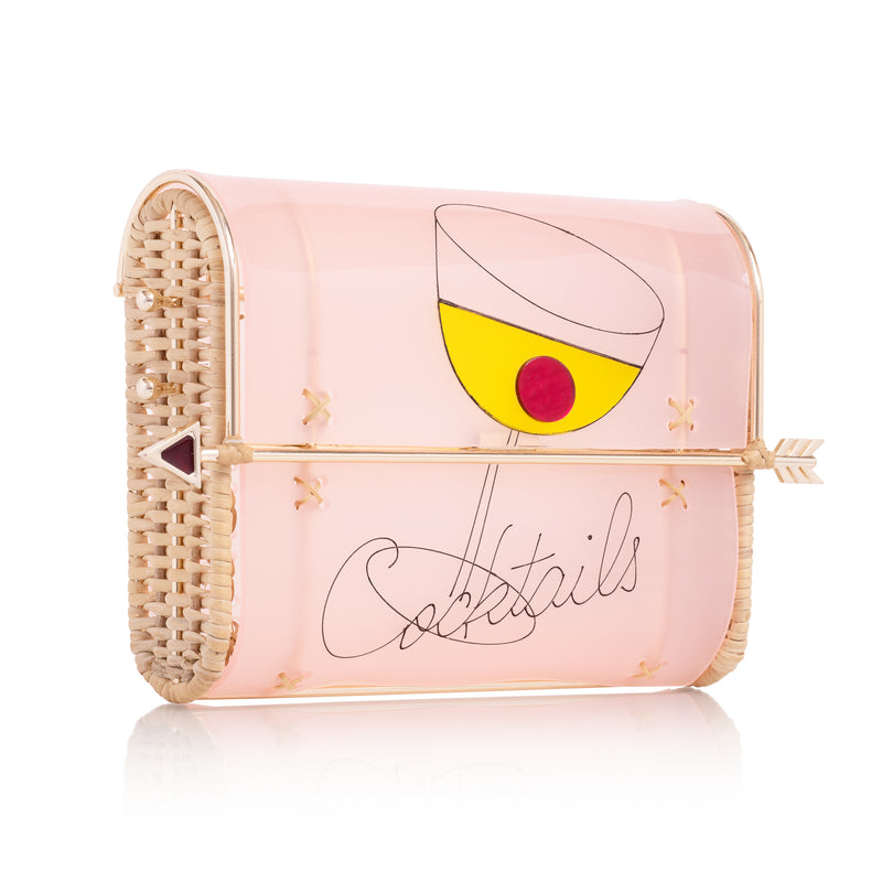 Clutch estruturada em acrílico rosa, com ilustração de taça de coquetel amarela, detalhe vermelho e fecho dourado em formato de flecha.