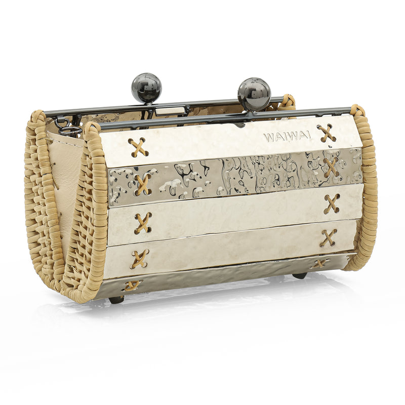 Clutch estruturada em metal prateado martelado com laterais em rattan, detalhe de costura em X e fecho esférico metálico.