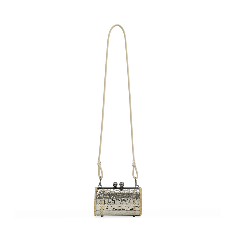 Clutch artesanal em metal prateado martelado com laterais em rattan, detalhe de costura em X e fecho redondo metálico.