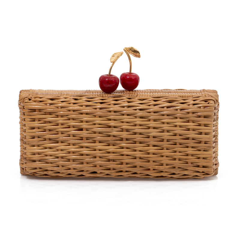 Clutch artesanal em rattan natural com design retangular e fecho em formato de cerejas vermelhas com folhas douradas.