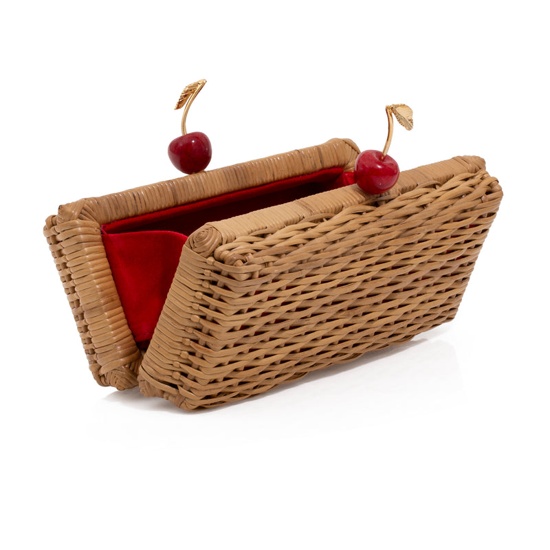 Clutch retangular em rattan natural com detalhe de fecho em cerejas vermelhas e folhas douradas.
