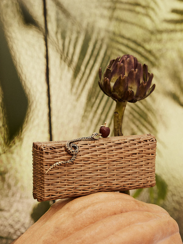 Clutch em rattan natural retangular com fecho decorado por serpente dourada e maçã vermelha.