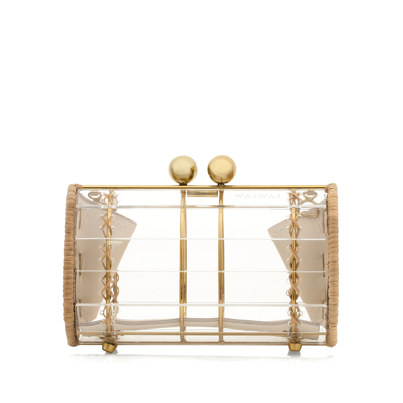 Bolsa clutch pequena estruturada em acrílico transparente, com laterais em rattan natural e detalhes de amarração em couro bege. Possui ferragens douradas e fecho superior com esferas metálicas douradas.