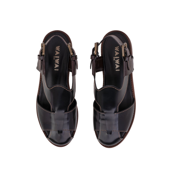 Sandália em couro preto com design fechado, fivela lateral ajustável e solado em madeira com acabamento sofisticado.