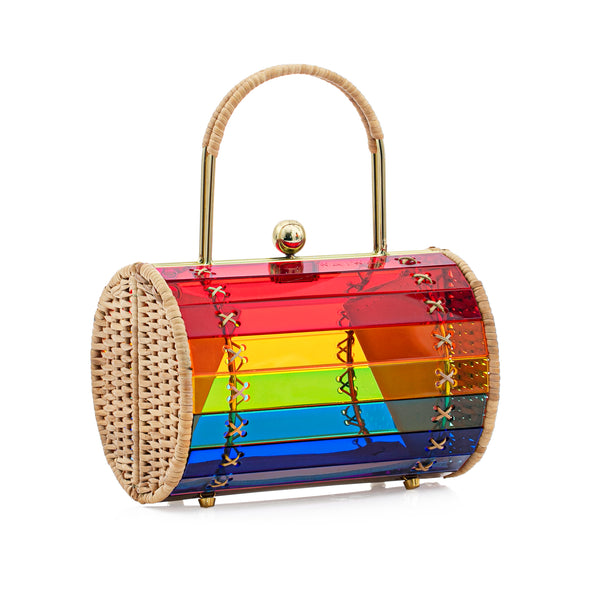 Bolsa em acrílico arco-íris estruturada, com laterais em rattan natural, alça rígida dourada e fecho metálico no topo. Design vibrante de inspiração geométrica.