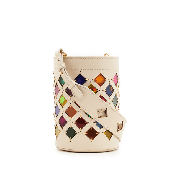 Bolsa bucket em couro branco com recortes geométricos em losangos, revelando fundo colorido em tons de arco-íris. Alça longa ajustável com detalhes vazados e ferragens douradas.
