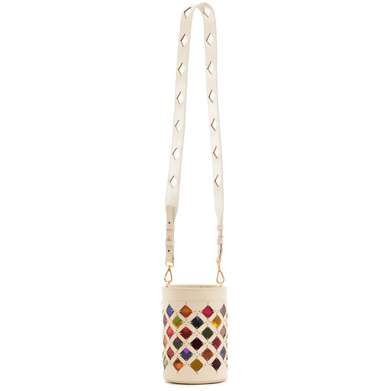 Bolsa bucket em couro branco com recortes geométricos em losangos, revelando fundo colorido em tons de arco-íris. Alça longa ajustável com detalhes vazados e ferragens douradas.