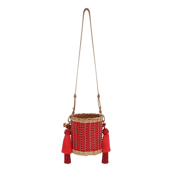 Bolsa bucket em palha trançada com detalhes em vermelho, alça longa em couro caramelo e tassels grandes em vermelho.