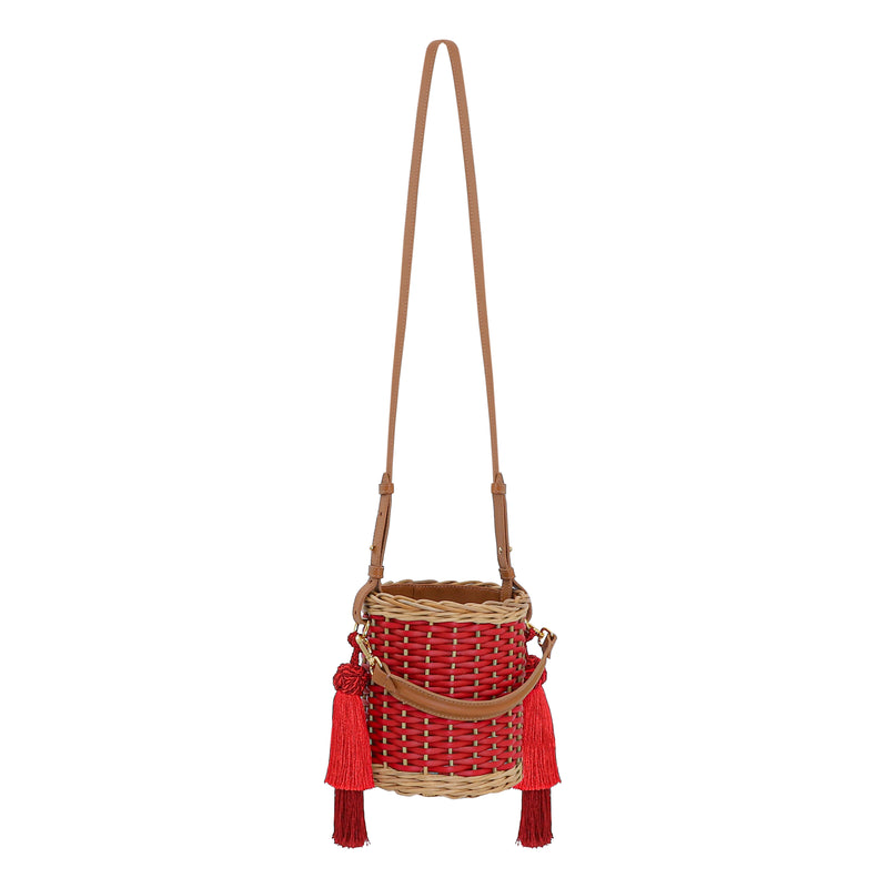 Bolsa bucket em palha trançada com detalhes em vermelho, alça longa em couro caramelo e tassels grandes em vermelho.