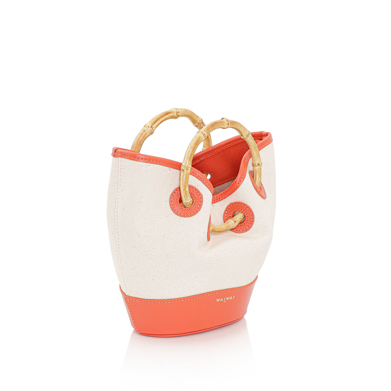 Bolsa em canvas cru com base e detalhes em couro laranja, alça curta em bambu e design estruturado.