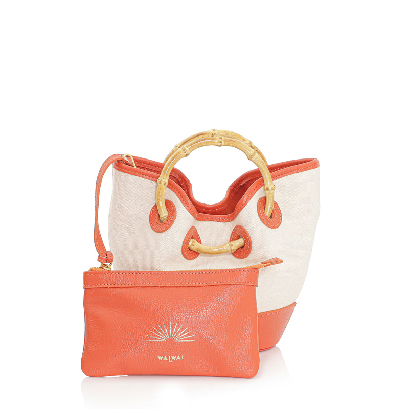 Bolsa em canvas cru com base e detalhes em couro laranja, alça curta em bambu e design estruturado.