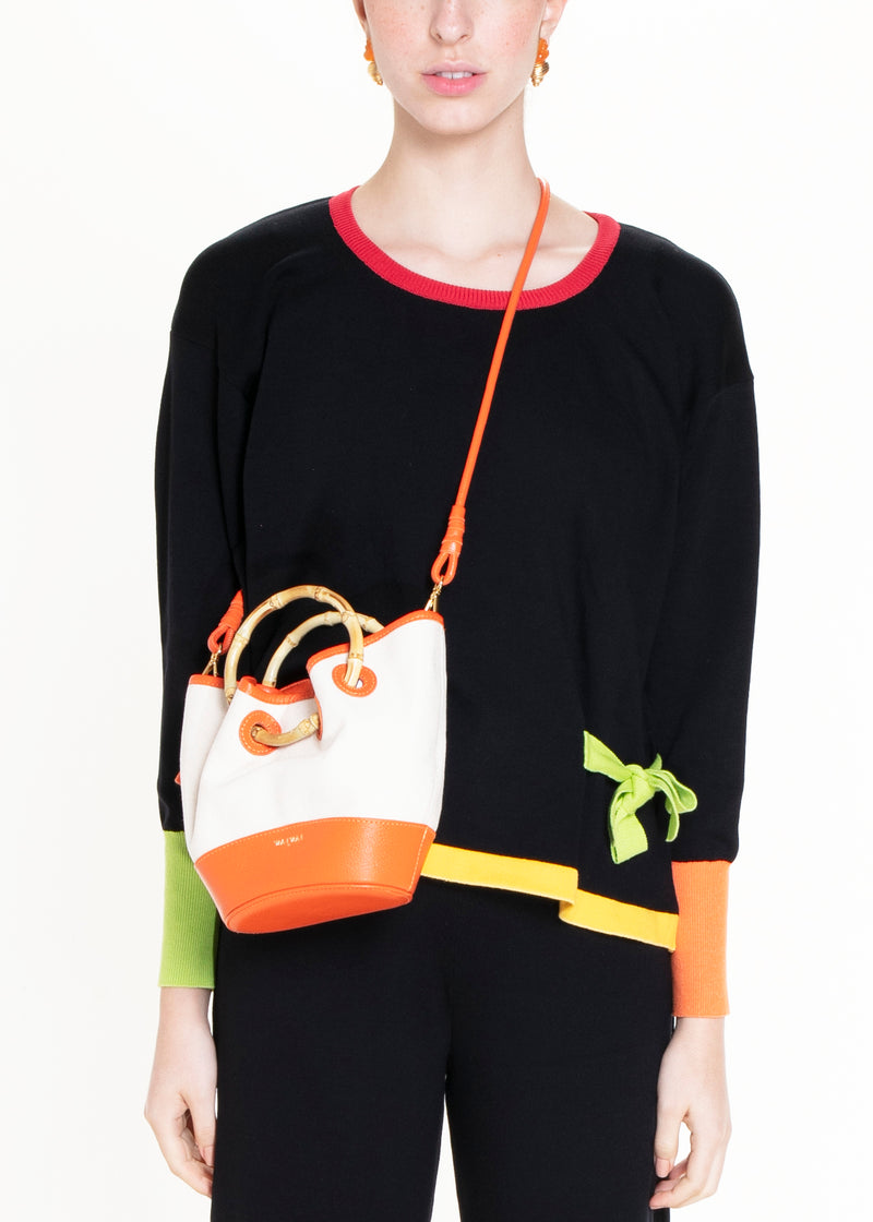 Bolsa em canvas cru com base e detalhes em couro laranja, alça curta em bambu e design estruturado.