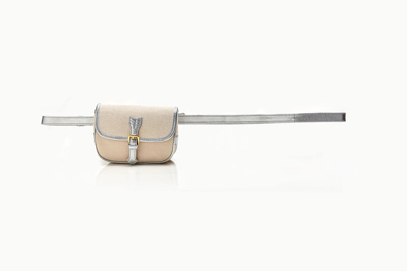 Bolsa de canvas cru estruturada, com acabamento em couro metálico prata, fivela dourada e opção de uso como tiracolo ou pochete.