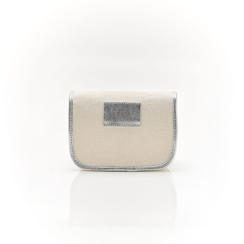 Bolsa em canvas cru com acabamento em couro prata metalizado e fecho em fivela dourada, prática e versátil para uso como crossbody ou pochete.